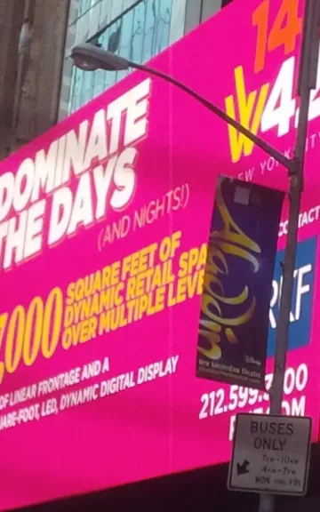 Digital billboard in Times Square displaying promotional text and pricing information in bright pink.