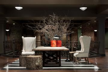 Elegant dining area with white chairs, dark wooden table, and illuminated decorative tree.