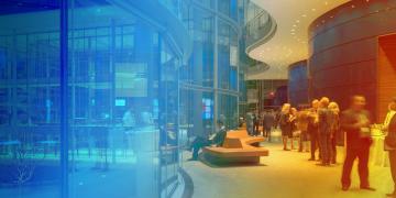 Modern architectural interior with blue-tinted glass wall and warm lighting in orange curved space.